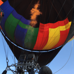 A view from beneath a hot air balloon with its burners ignited, showing the colorful fabric of the balloon's canopy.