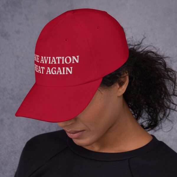 A woman wearing a red hat with the words " we aviation that again."