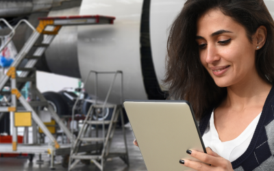 a woman holds a tablet in an airplane hanger