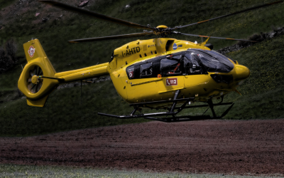 a yellow helicopter sits on a ridge